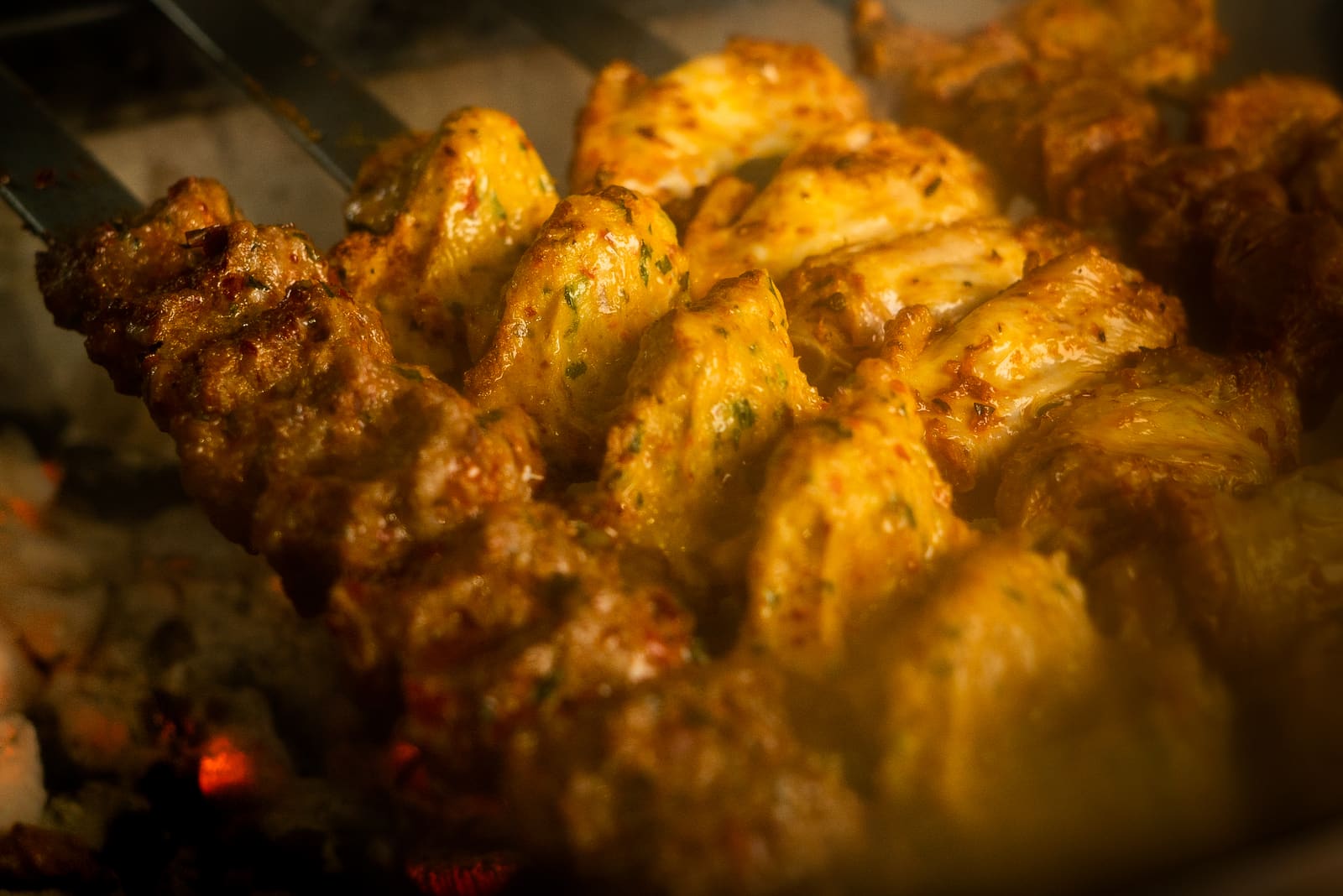 Marinated chicken pieces turning golden over the open charcoal