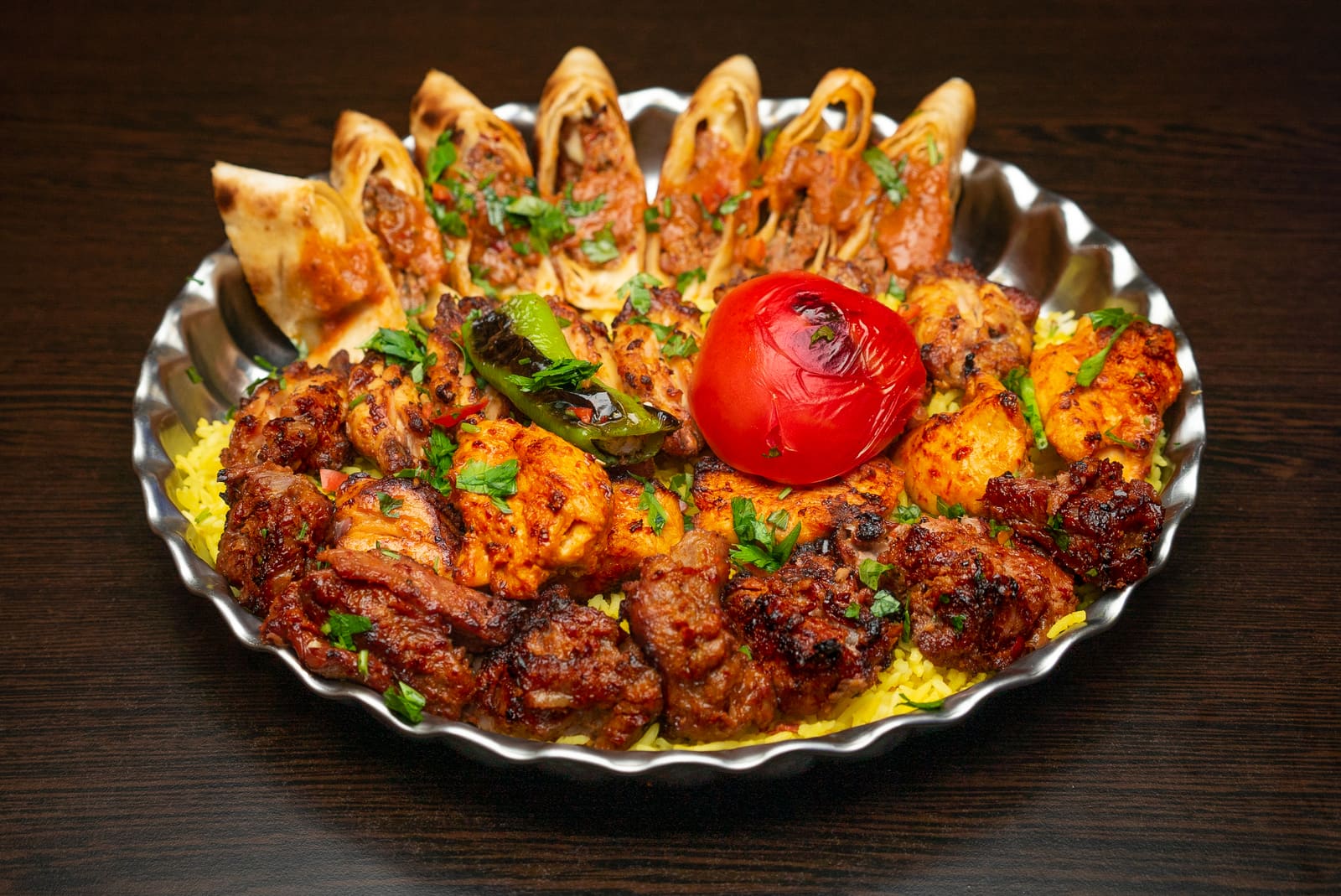 A sharing platter of charcoal-grilled lamb, chicken, kofte and rolled beyti on rice, with a grilled tomato in the middle