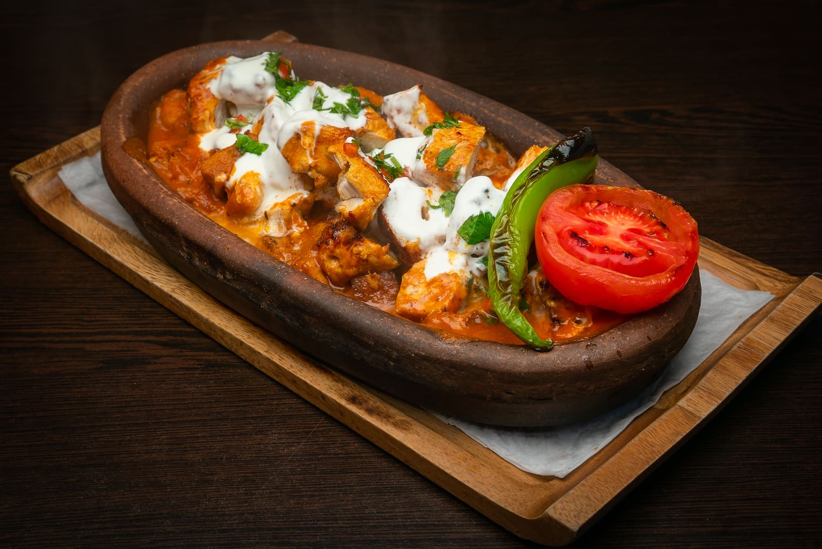 Charcoal-grilled chicken in butter and tomato sauce, finished with yoghurt, in a clay dish